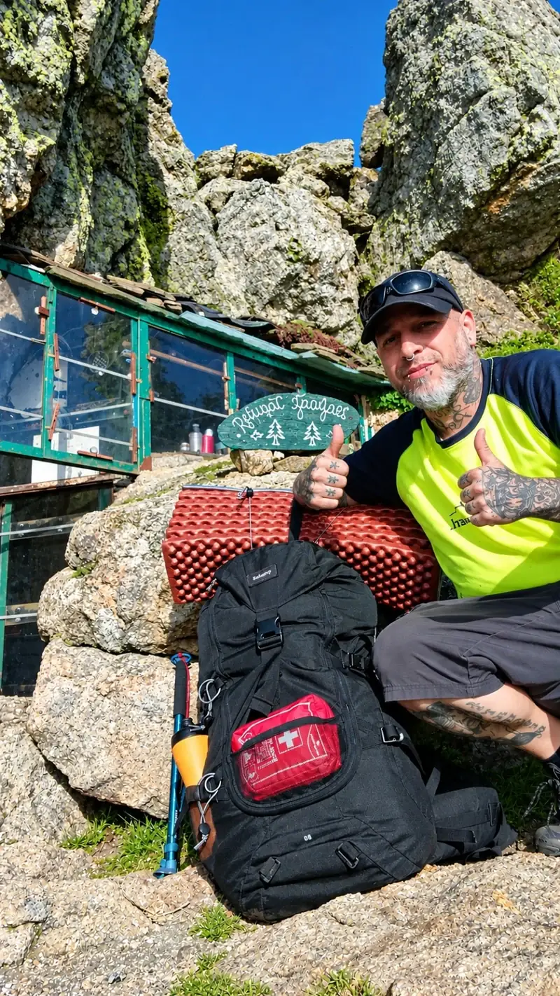 Tete con su mochila junto a un refugio de montaña